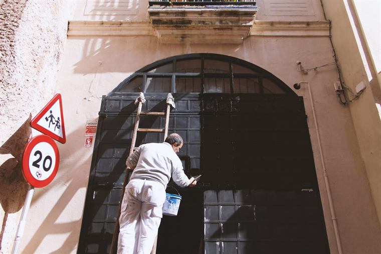Handwerker auf einer Leiter an einer Hausfassade