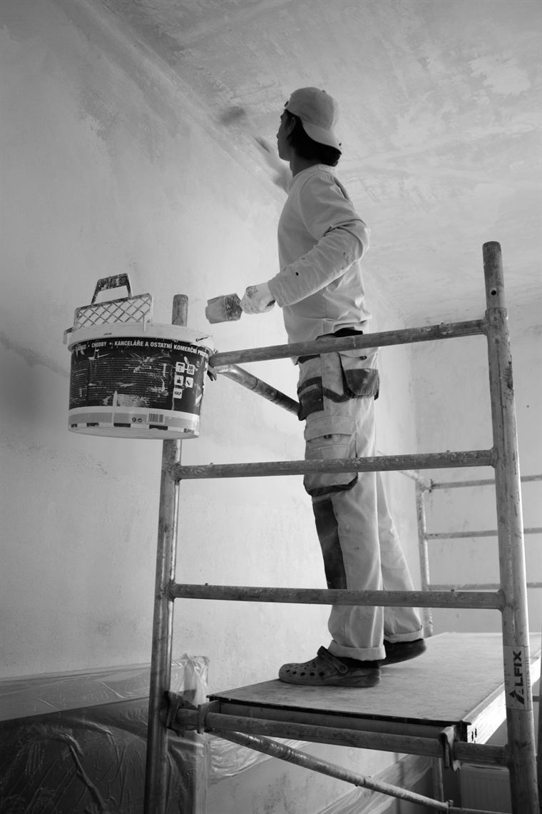 Maler auf einem Gerüst streicht eine Wand